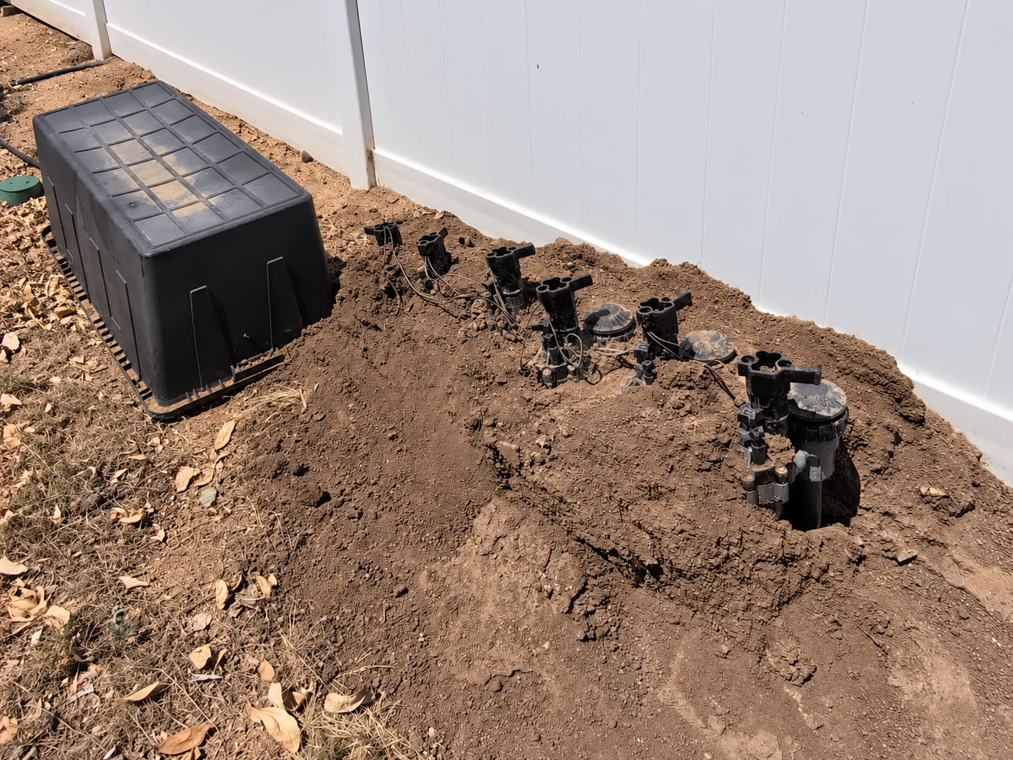 Exposed sprinkler and irrigation lines within gopher-damaged soil